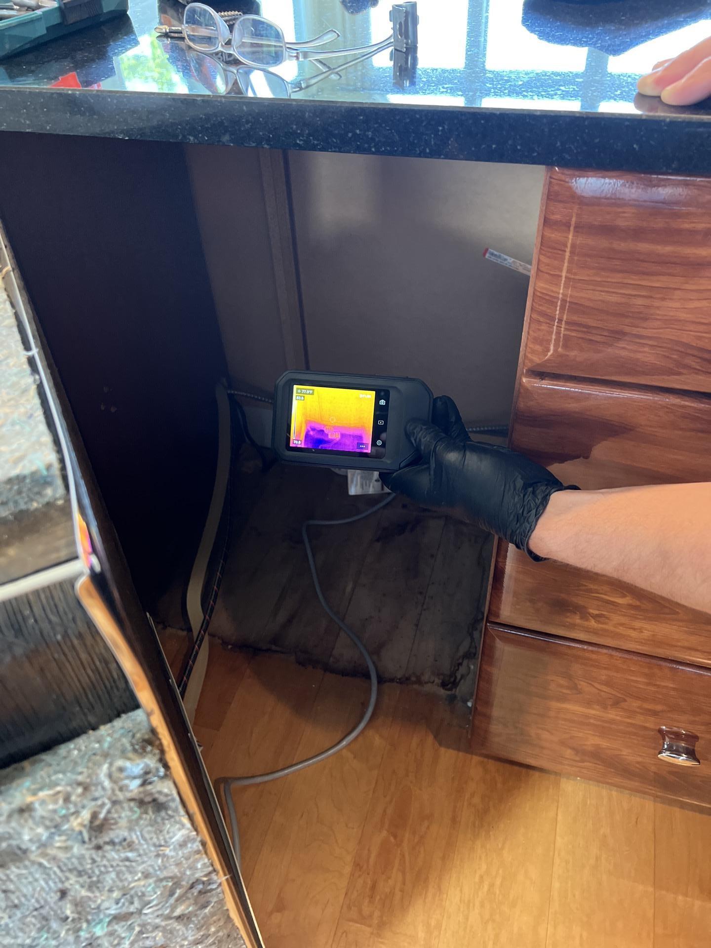 Thermal imaging used to detect hidden moisture beneath kitchen cabinetry during water mitigation