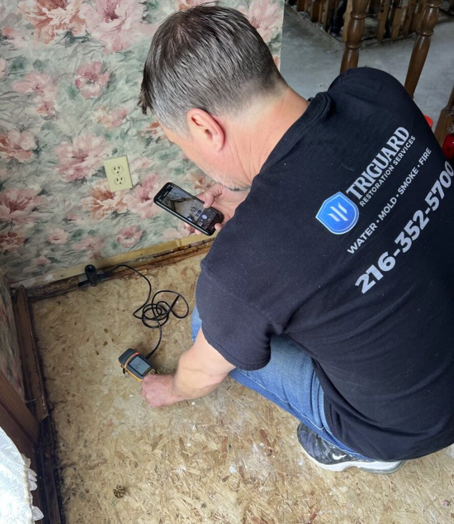 Water damage technician using moisture meter to document hidden moisture for insurance claim in Parma and Independence Ohio home.