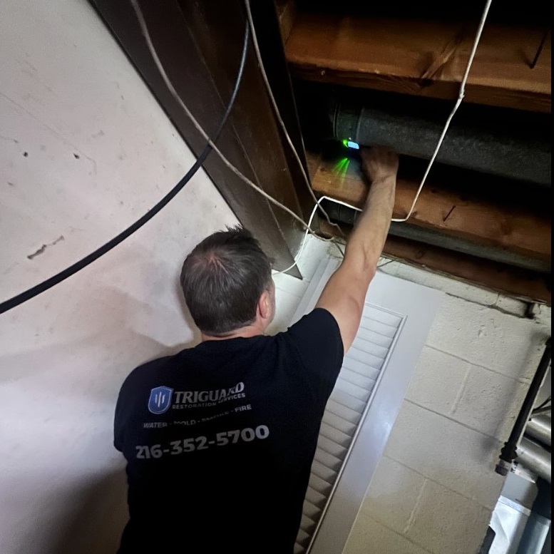 TriGuard Restoration technician checking a basement ceiling pipe with a moisture meter in Shaker Heights, OH