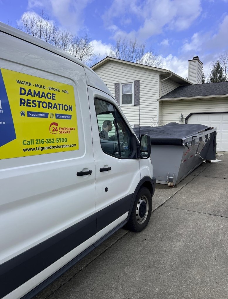 TriGuard Restoration van and debris dumpster parked outside a home during a water damage job in Parma, OH